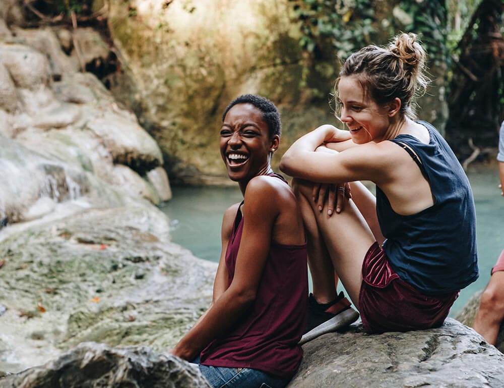 Two women outside by a small lake